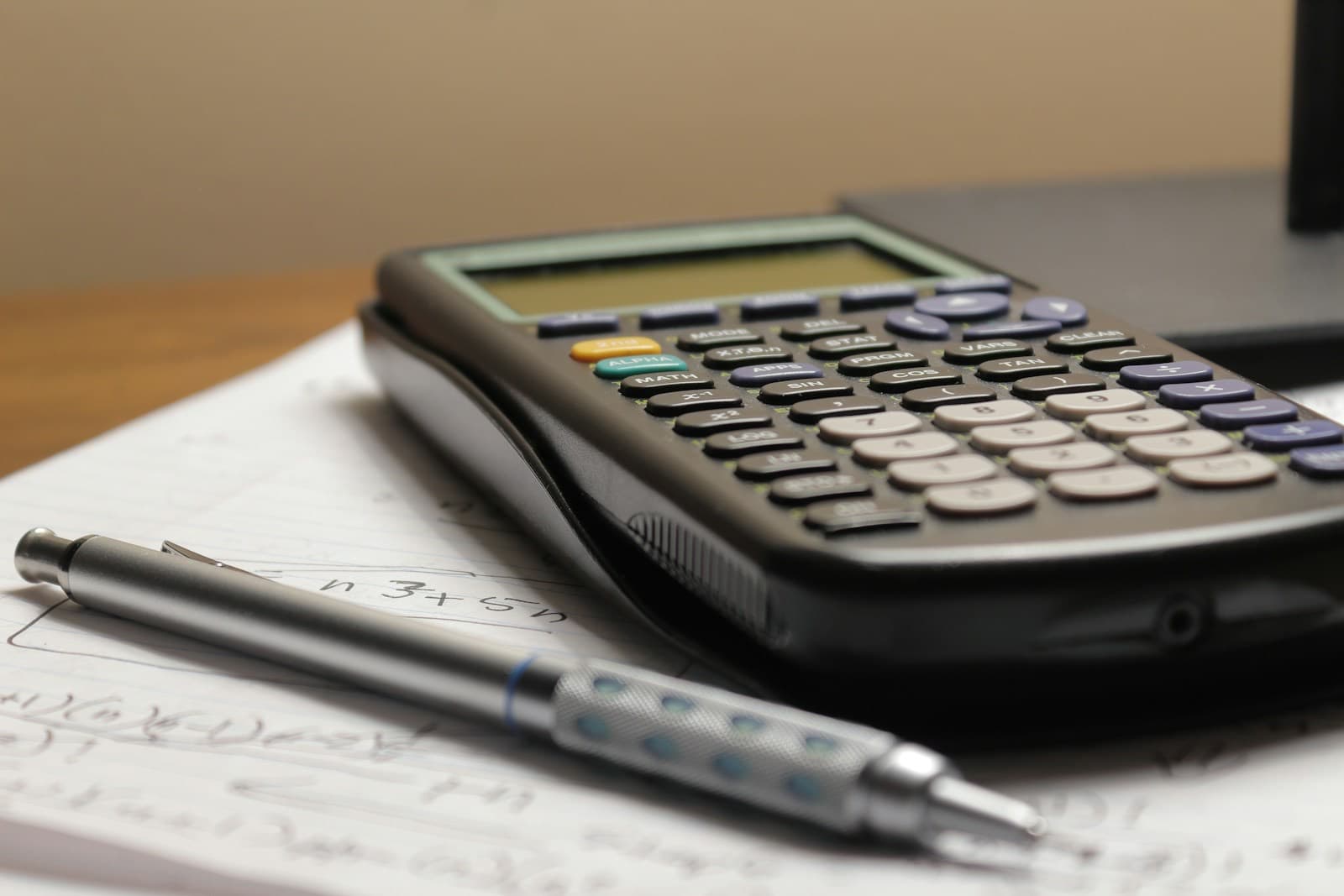 A calculator and a pencil on a page of handwritten sums
